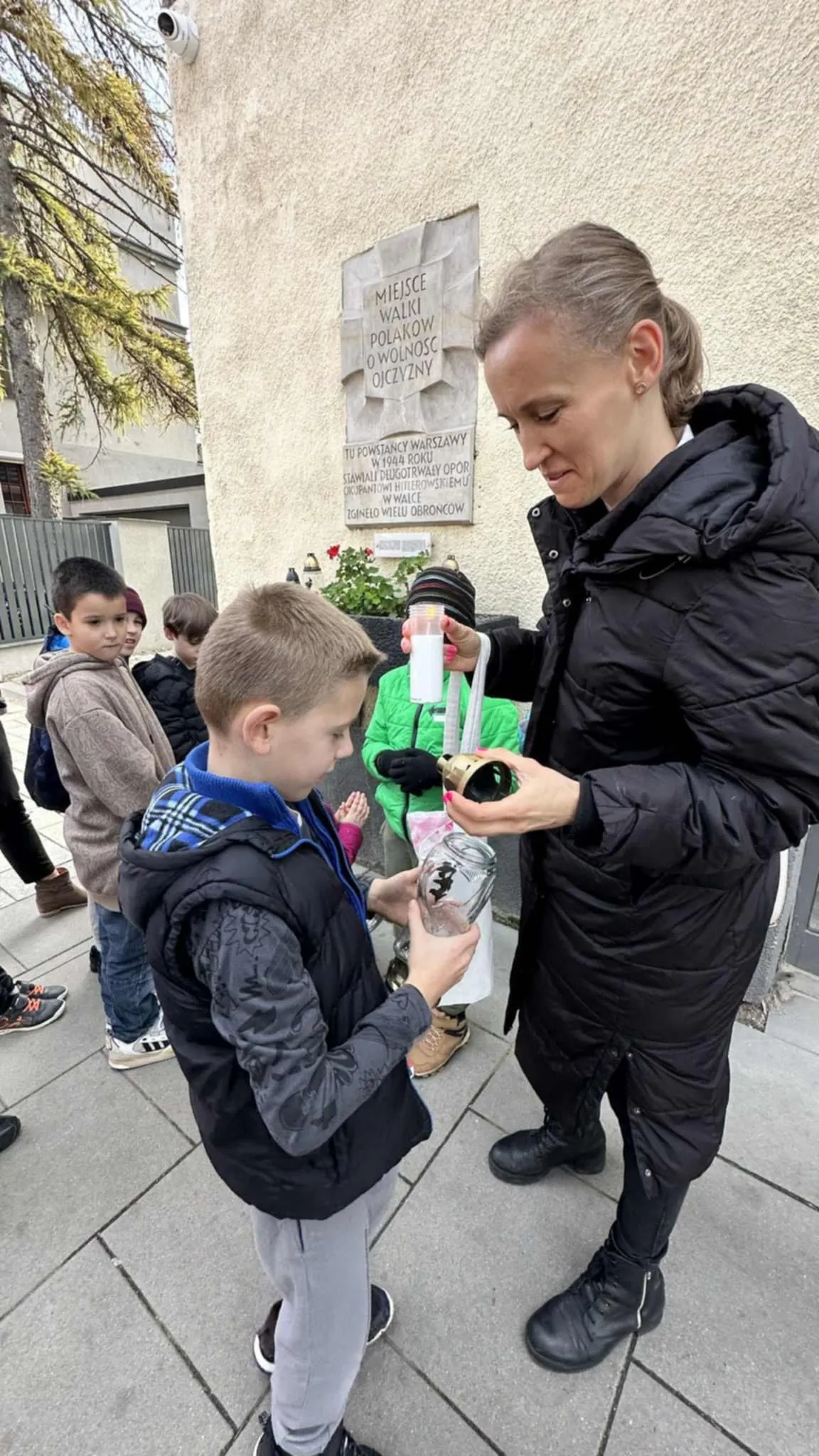 Uczeń wraz z nauczycielem zapala znicz