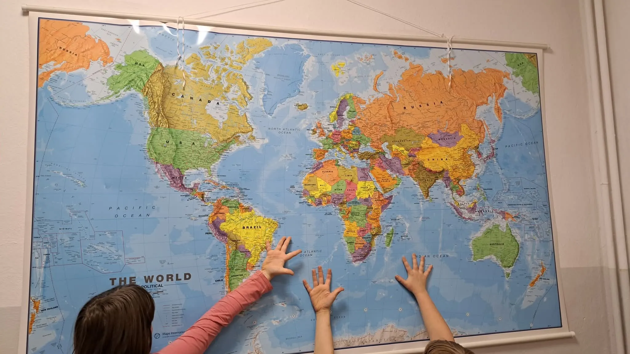 Uczniowie korzystają z mapy świata podczas zajęć